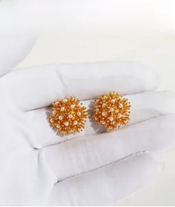 Macro view of vintage fireworks pearl earrings with intricate gold floral clusters
