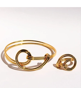 Close-up of gold knotted wire bracelet and matching ring set with polished metallic finish