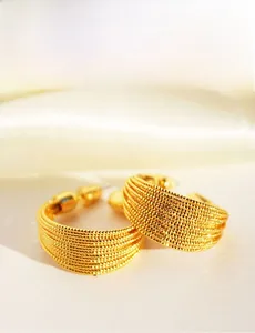 Detailed close-up of gold layered brushed metal C-shape hoop earrings on silk