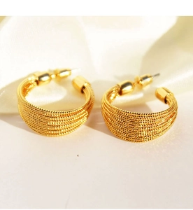 Detailed view of layered brushed gold hoop earrings on elegant white silk background