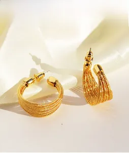 Detailed macro view of gold C-shaped earrings with intricate multi-layer woven texture