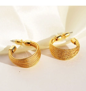 Detail view of gold C-shaped earrings with textured multilayer brushed metal finish
