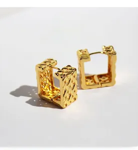 Detail view of square gold plated brass earrings featuring a woven mesh texture and zircon