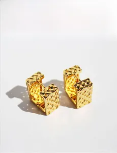 Detail of gold square earrings featuring a woven lattice pattern and polished finish