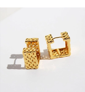 Macro detail of gold square hoop earrings with intricate woven lattice texture finish