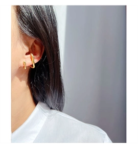 Close-up of minimalist gold ear cuff with irregular textured metal design worn by a model