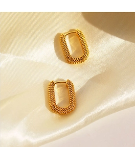 Detail of vintage gold-plated U-shaped earrings with textured beaded pattern on silk