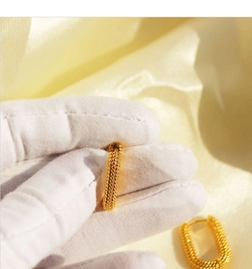 Macro view of gold U-shaped earrings with fine granulated texture on silk background