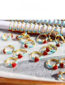 Macro shot of blue enamel hoop earrings with red heart pendants in gold-plated metal