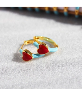 Macro shot of blue enamel heart hoop earrings with gold-toned metal detailing