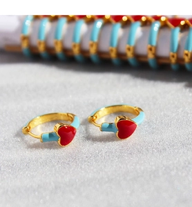 Macro shot of gold hoop earrings with blue enamel finish and vibrant red heart charms
