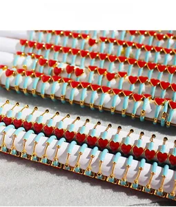 Detailed view of gold earrings with blue enamel finish and red heart patterns