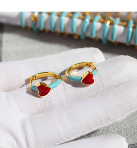 Detailed view of handmade blue and red heart-shaped enamel hoop earrings in gold finish