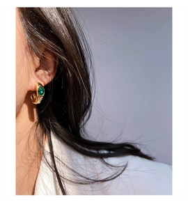 Détail de créoles en laiton plaqué or en forme de C avec zircon émeraude verte