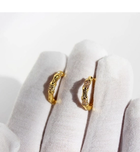 Macro view of gold bamboo hoop earrings with sparkling cubic zirconia settings