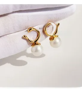 Detailed shot of gold-plated brass geometric earrings with large round pearls and zircons