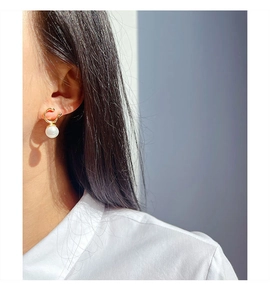 Close-up of elegant gold geometric earrings with round faux mabe pearl on a model
