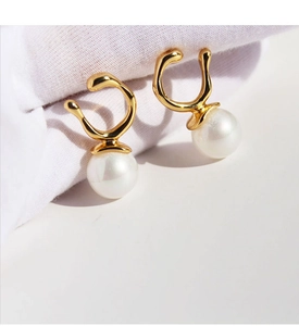 Macro view of gold geometric hooks with iridescent white pearls on white textured fabric
