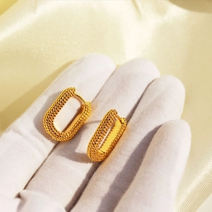 Golden U-shaped earrings with vintage beaded texture on luxurious yellow silk background