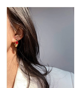 Gros plan de boucles d'oreilles vintage en forme de C plaquées or avec rubis ovale éclatant