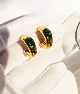 Gros plan de boucles d'oreilles en C plaquées or avec zircons vert émeraude ovales