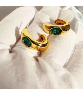 Gros plan de boucles d'oreilles C vintage plaquées or avec une grande émeraude zircon