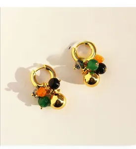 Macro detail of gold plated brass earrings featuring colorful beads and a polished gold sphere