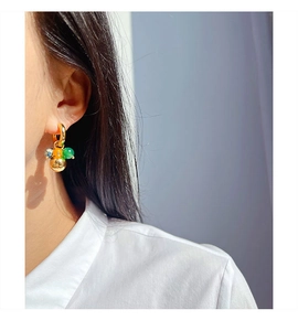 Detail of vintage gold hoop earring with green, orange, and floral beads on a model