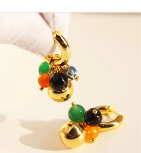Detailed view of gold hoop earrings with multi-colored agate beads and a golden sphere
