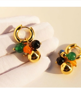 Close-up of bohemian hoop earrings with green, orange, black beads and gold ball drop