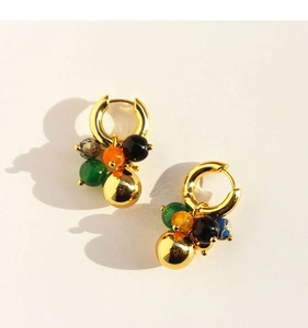 Macro shot of gold hoop earrings with green, orange, and black agate beads with a center gold ball