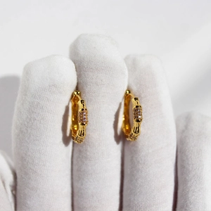 Minimalist golden bamboo hoop earrings with sparkling cubic zirconia on white background