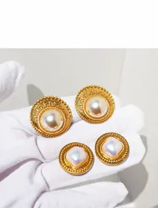 Dettaglio di orecchini vintage dorati con perle grandi e motivi barocchi in pizzo
