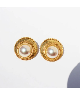 Dettaglio di orecchini vintage in pizzo dorato con perle e decorazioni metalliche