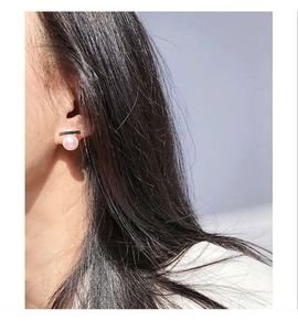Close-up of pearl stud earrings with minimalist metal bar on model's ear