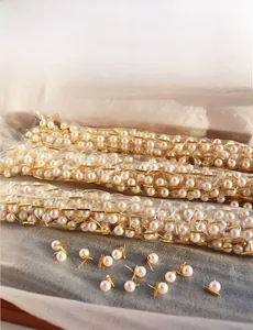 Detailed view of round pink pearl earrings with gold bar studs on grey felt