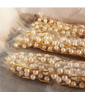 Detailed wholesale view of minimalist white pearl earrings with golden bar studs