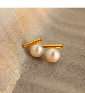 Macro shot of French style pearl stud earrings with gold bar and pink luster finish