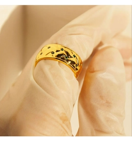 Macro detail of vintage gold lattice ring with green zircon stones on finger
