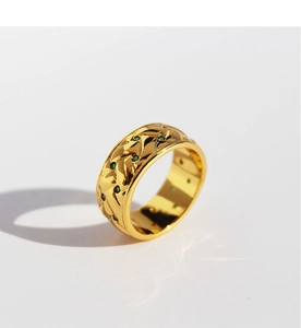 Detailed macro view of gold-plated quilted wide ring featuring small green zircon stones