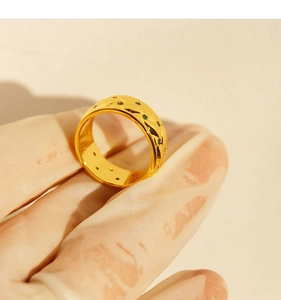 Macro view of vintage gold-plated wide ring with green zircon and black geometric details