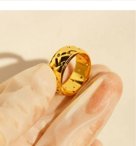 Detailed shot of a wide gold ring with textured pattern and inlaid green zircon stones