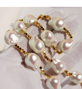 Dettaglio macro di collana con perle barocche dai riflessi iridescenti e grani dorati