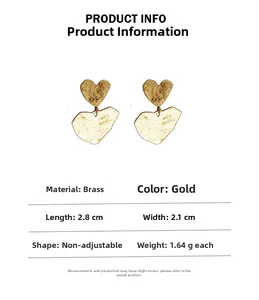 Detail view of gold brass heart earrings with pleated texture and product measurements