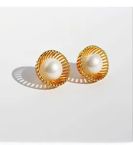 Gros plan de boucles d'oreilles ajourées dorées avec une grande perle centrale