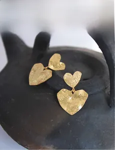 Detail of gold heart earrings with hammered texture on vintage ceramic plate