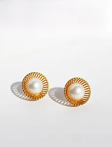 Détail macro de boucles d'oreilles nid dorées avec perles blanches rondes polies