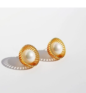 Vue macro de boucles d'oreilles nid d'oiseau dorées avec des perles blanches brillantes