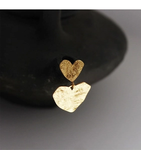 Macro detail of gold vintage wrinkled heart earrings with hammered metal texture
