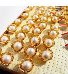 Gros plan de boucles d'oreilles perles avec motif nid d'oiseau doré sur un présentoir